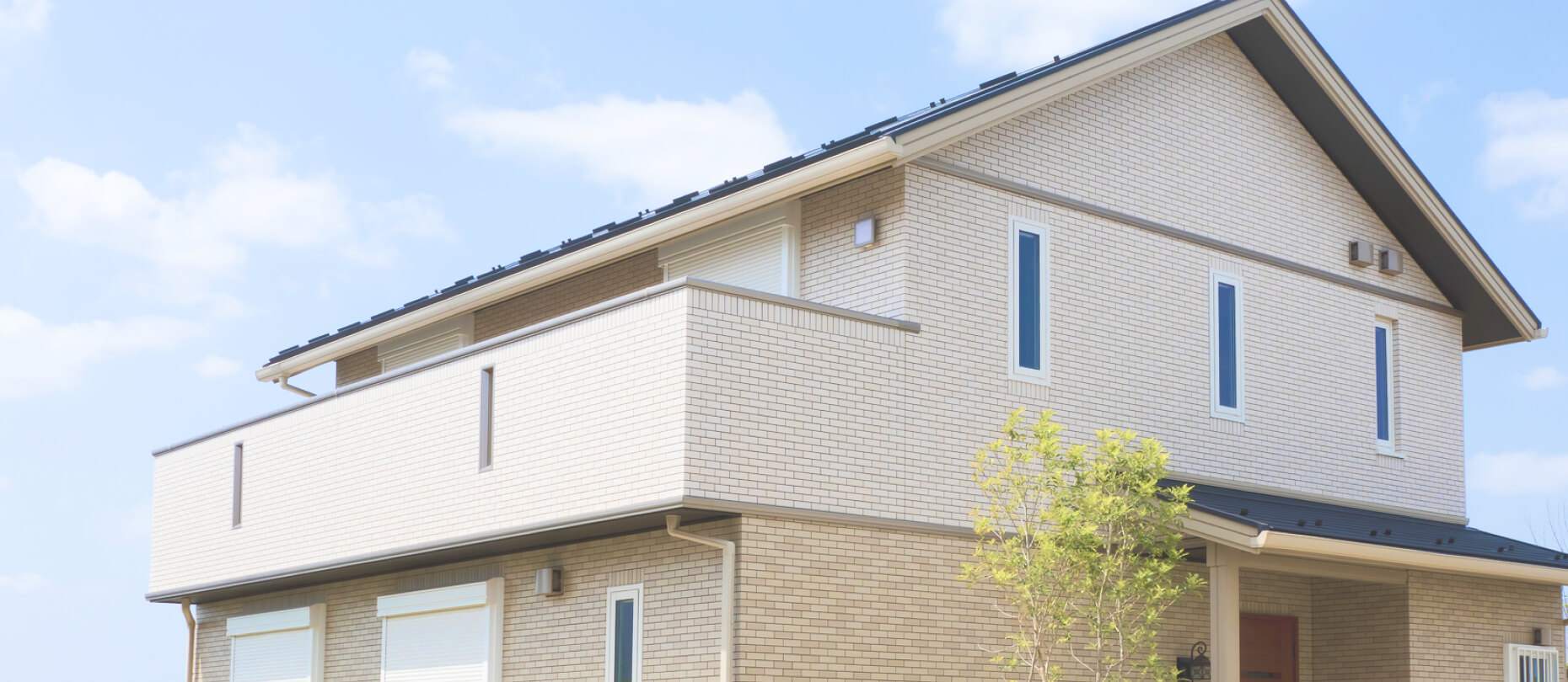 一軒家の外観: 青い空を背景にした、モダンなデザインの2階建ての住宅。