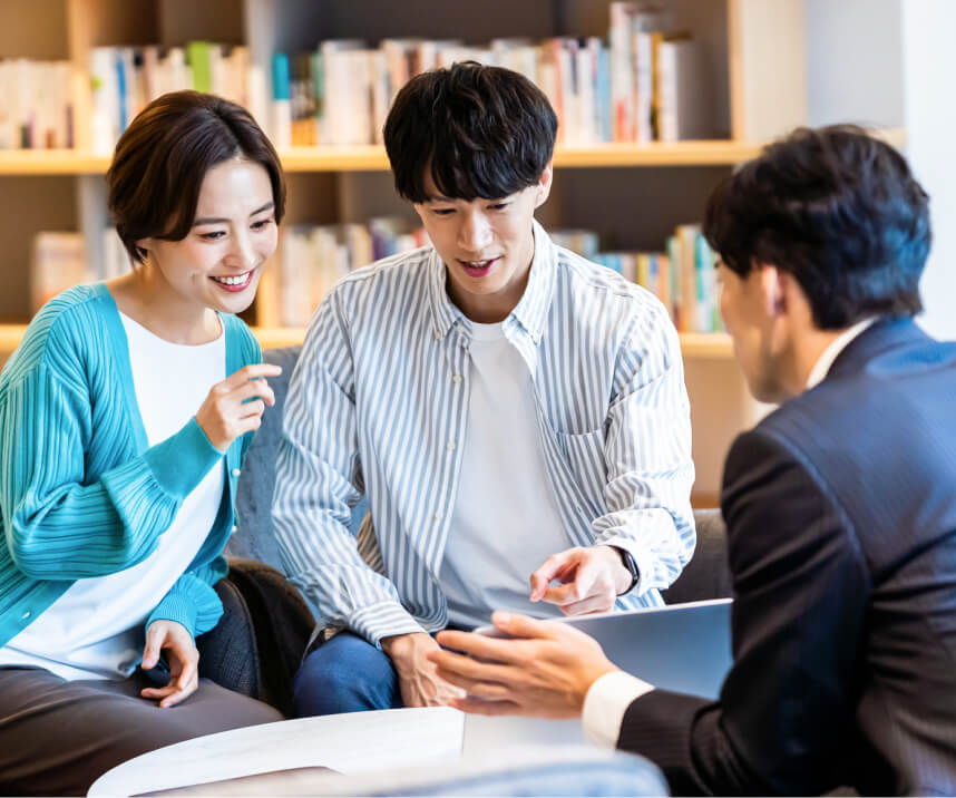 相談する夫婦: 本棚の前で、担当者の説明を笑顔で聞く夫婦。