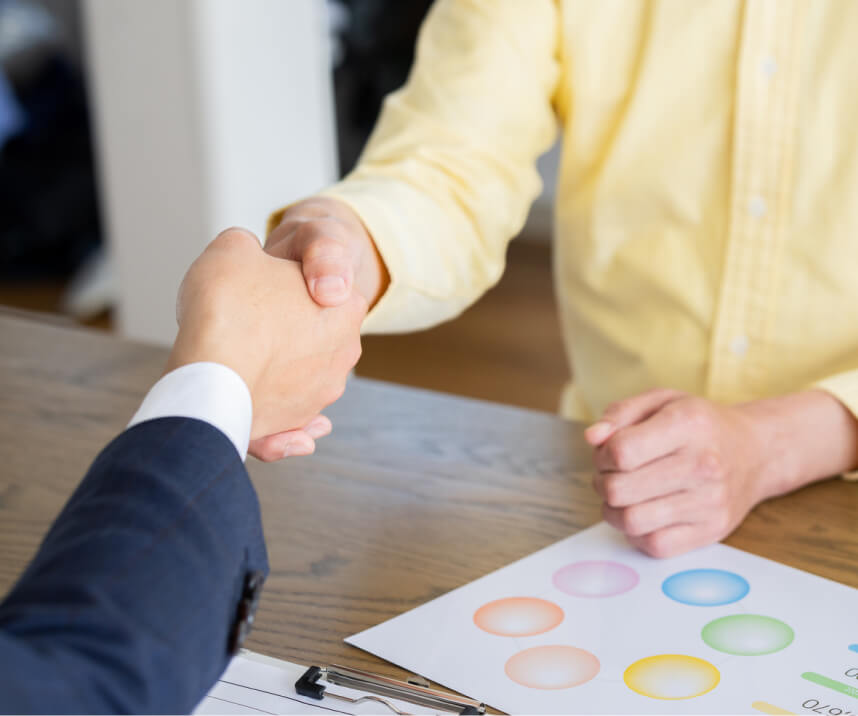 握を交わす二人: 成立し、テーブル越しに力強く握手を交わす様子。