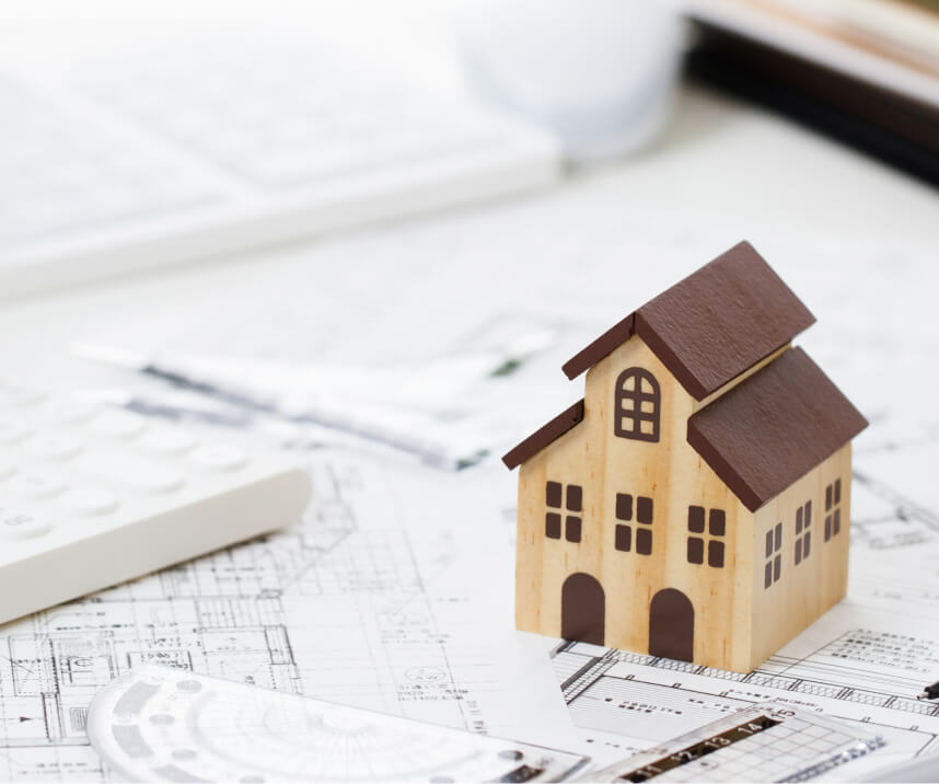 住宅模型と図面: 設計図の上に置かれた、木造2階建て住宅の小さな模型。