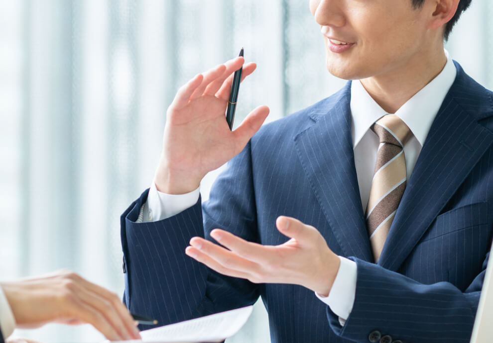 説明するビジネスマン: 資料を前に、身振り手振りを交えて熱心に説明する男性。