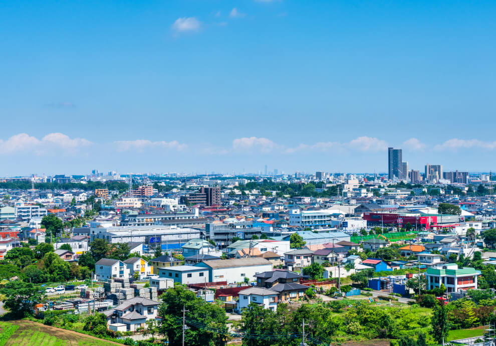 街並みの俯瞰: 青空の下に広がる、住宅やビルが立ち並ぶ穏やかな街並み。